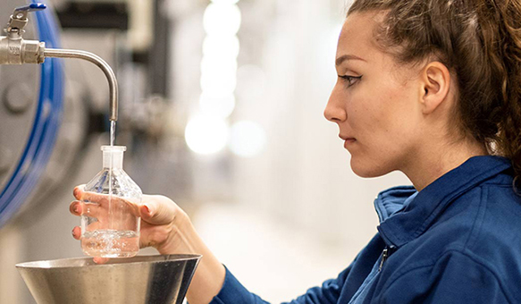 Junge Frau zapft Rohwasser in einem Wasserwerk