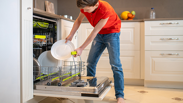 Junge räumt Geschirrspülmaschine ein