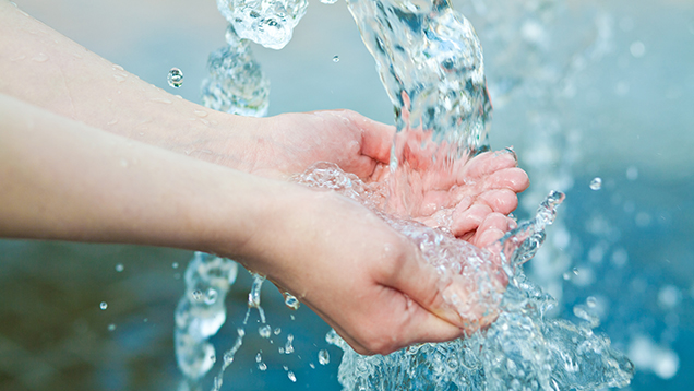 Kinderhände unter einem Wasserstrahl